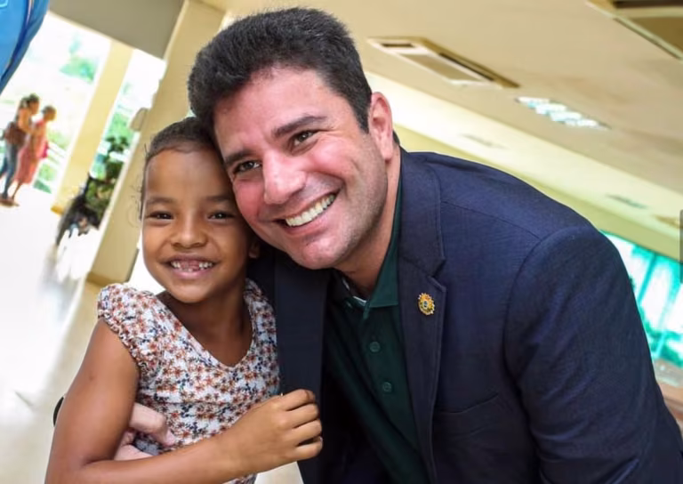 Gladson Cameli sorri abraçado a uma menina