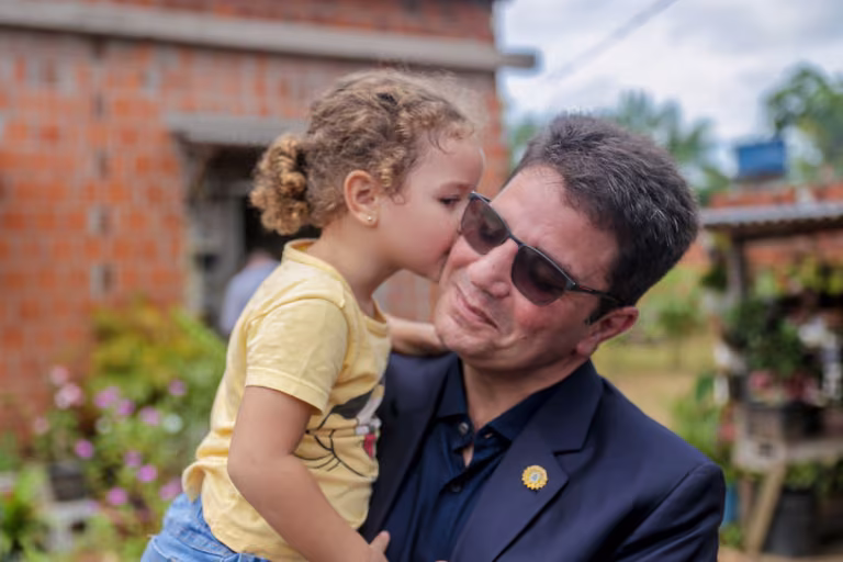 Uma menina dá um beijo no rosto de Gladson Cameli