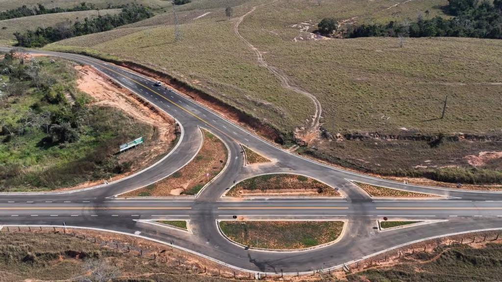 Vista aérea de um trevo de estrada asfaltada entre campos verdes