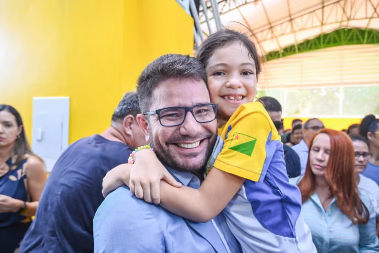 Gladson Cameli abraça uma menina com camiseta nas cores do Acre