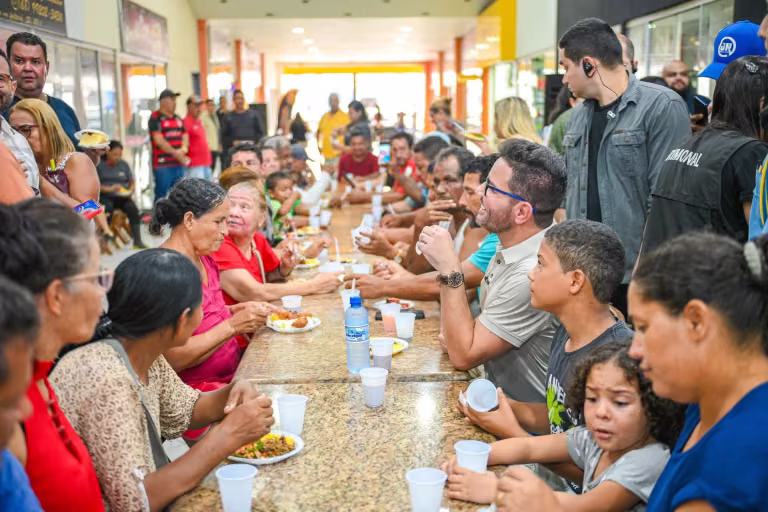 Gladson Cameli conversa com moradores em uma mesa de refeição comunitária