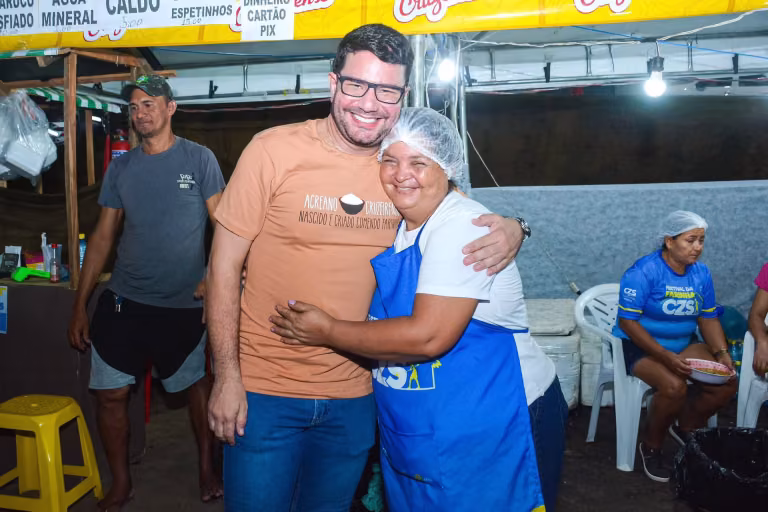 Gladson Cameli abraça uma trabalhadora de touca em uma cozinha de produção